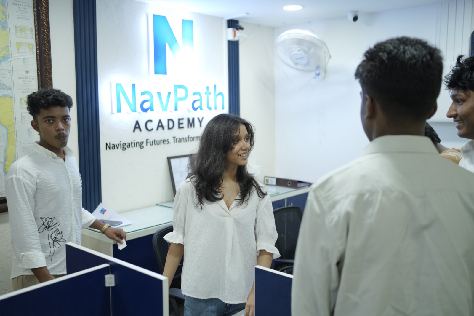 A student smiling at the NavPath Academy reception, with the NavPath logo wall behind