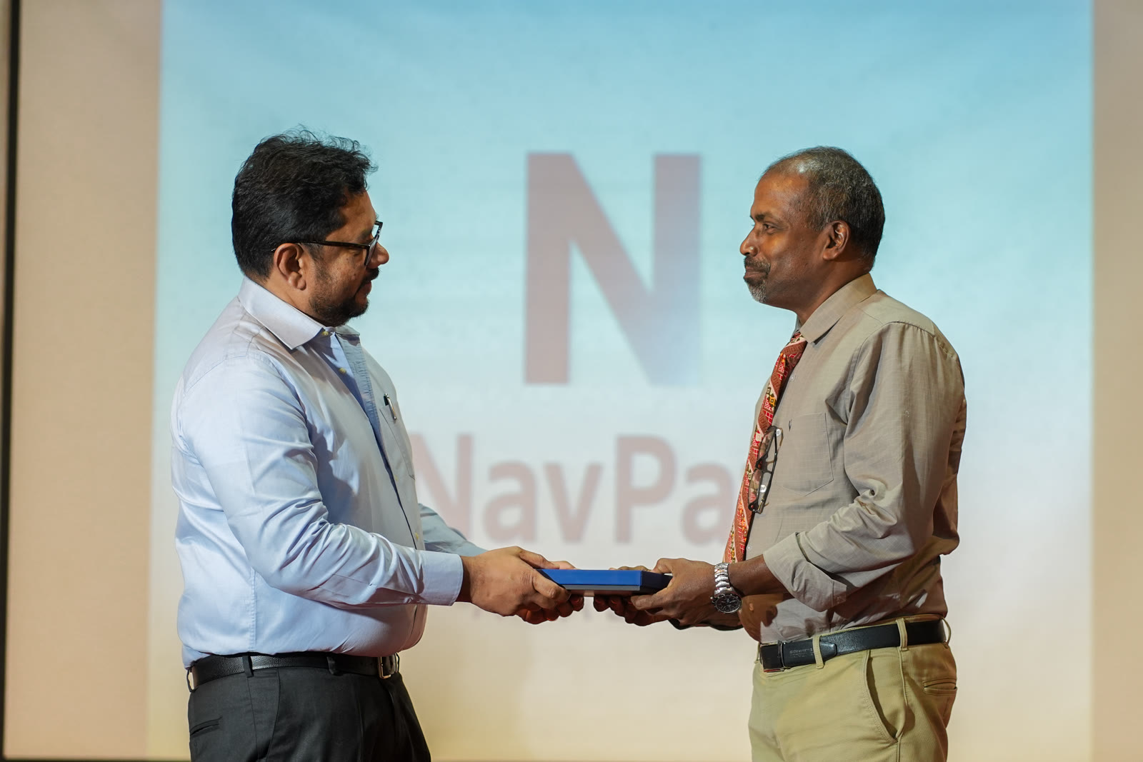 Award handshake on stage at a NavPath Academy event