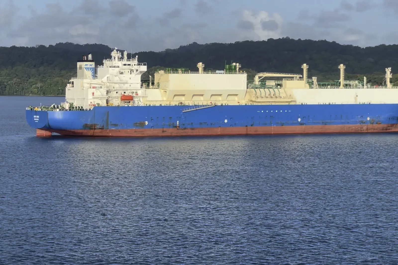 A blue-hulled LNG carrier passing through a canal lake