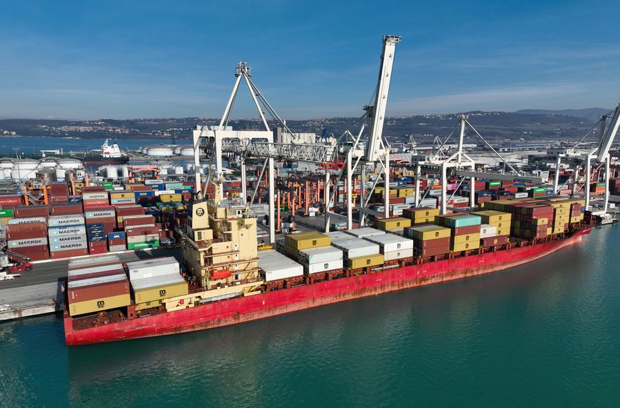 A large container ship berthed at a terminal, stacked high with boxes
